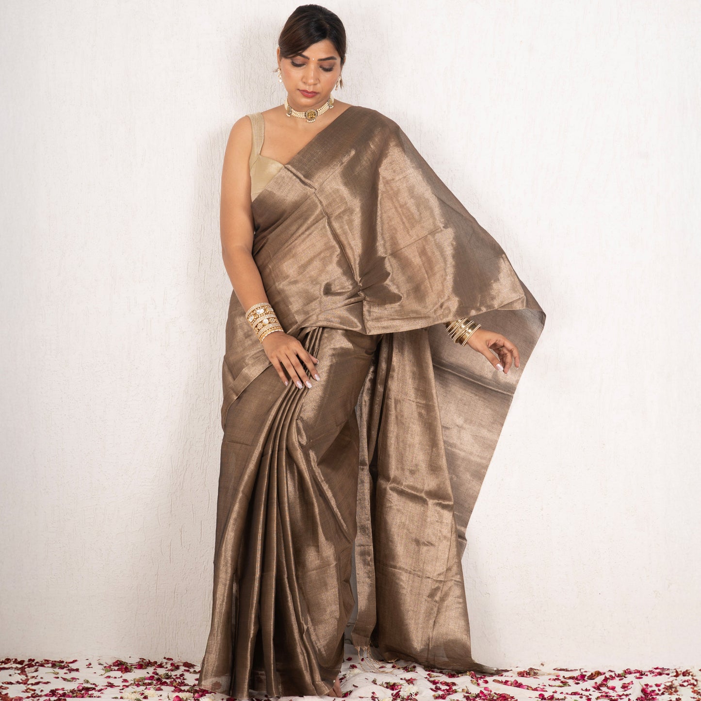 Woman wearing a bronze saree with a plain background