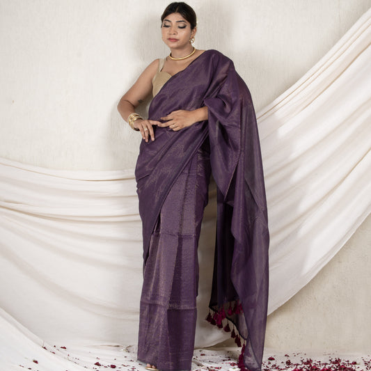 Woman wearing a purple saree against a white draped fabric background