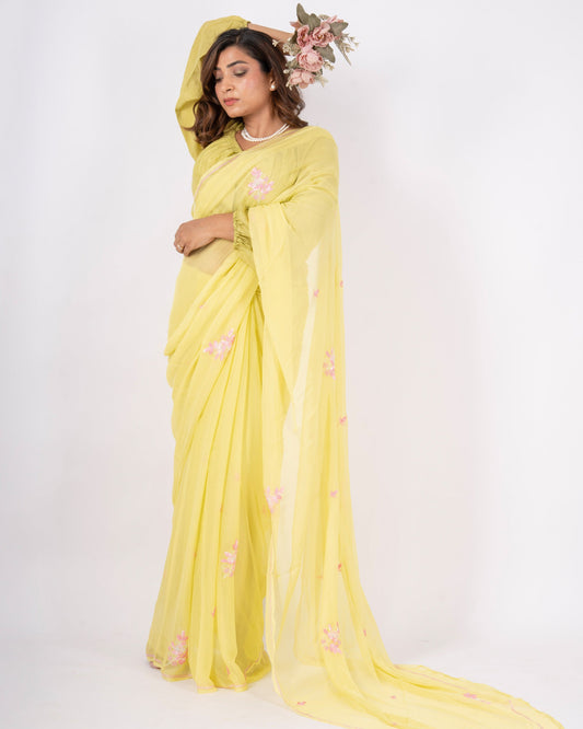 Woman wearing a yellow saree with a floral headpiece on a white background