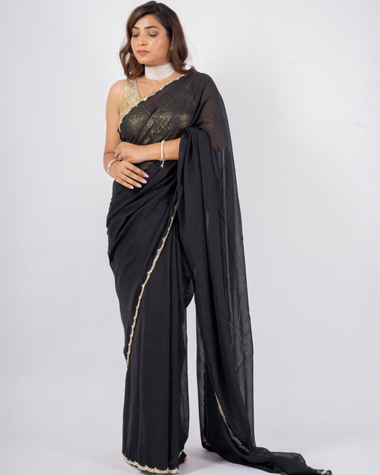 Woman wearing a black saree with a white blouse on a white background