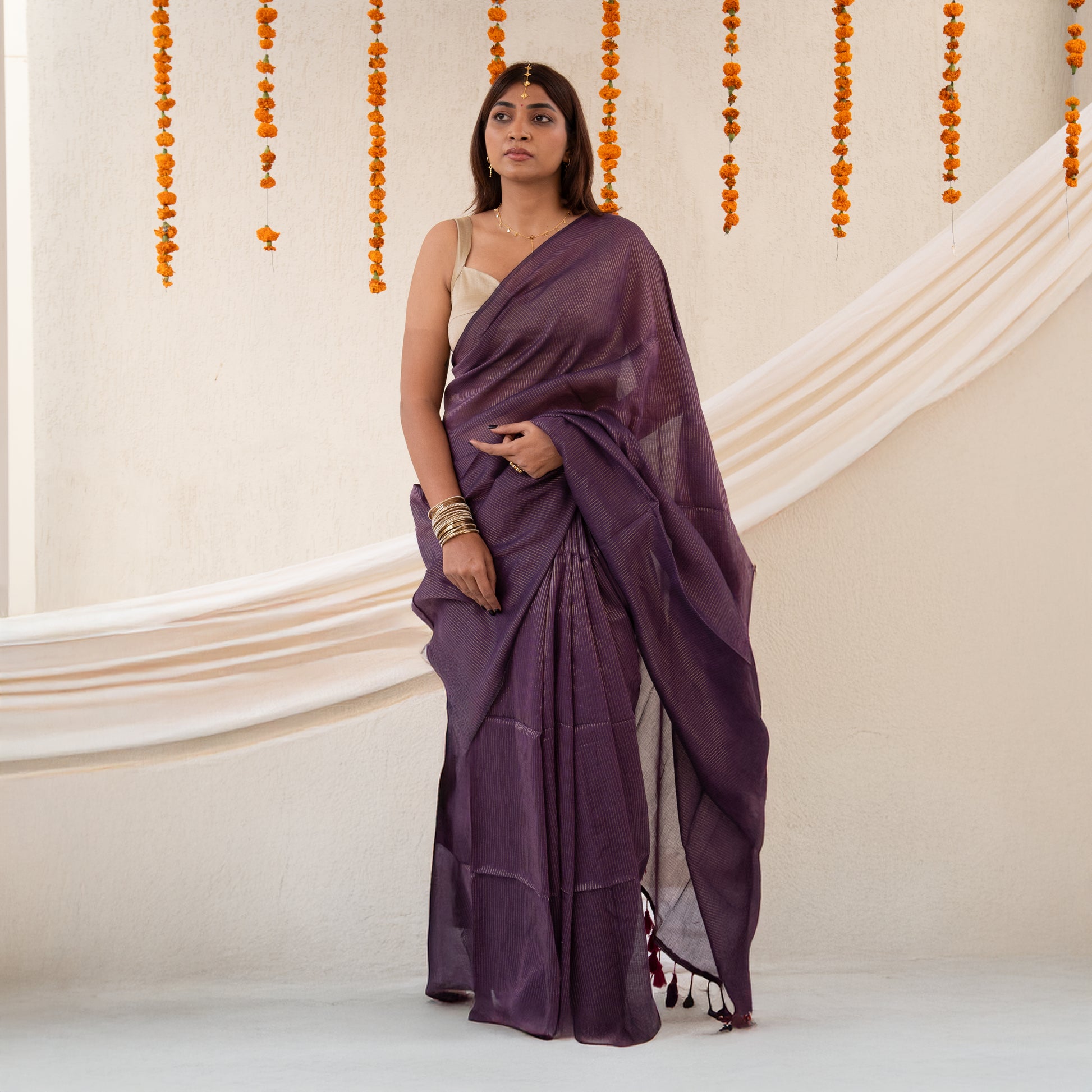 Woman wearing a purple saree with a neutral background