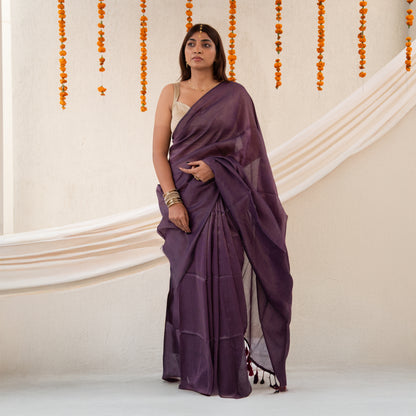 Woman wearing a purple saree with a neutral background