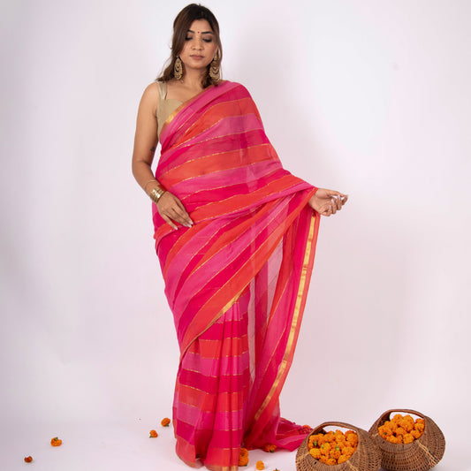 Woman wearing a vibrant pink and orange saree with two baskets of oranges on a white background