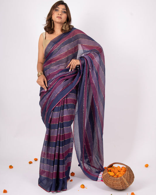 Woman wearing a blue and purple striped saree with a basket of oranges on a white background