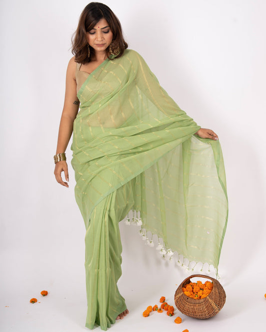 Woman wearing a light green saree with a white border on a white background