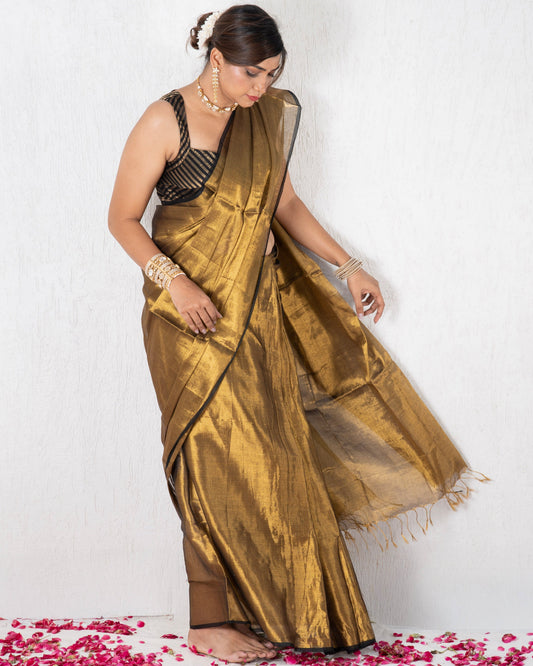 Woman in a gold saree standing on pink and white rose petals against a white background