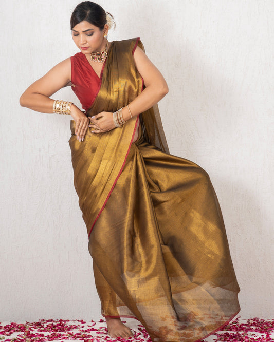 Woman in a gold saree with a red blouse standing on a white background with rose petals.