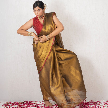 Woman in a gold saree with a red blouse standing on a white background with rose petals.