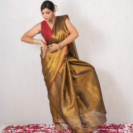 Woman in a gold saree with a red blouse standing on a white background with rose petals.