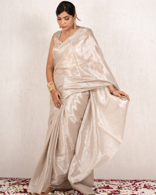 Woman wearing a beige saree with a white background