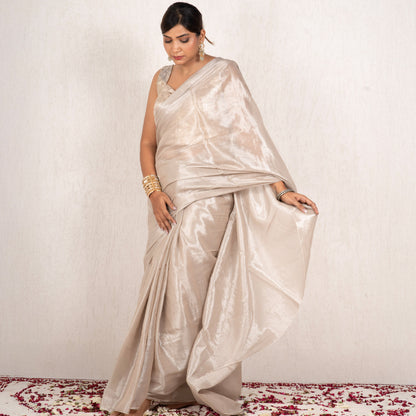 Woman wearing a beige saree with a white background