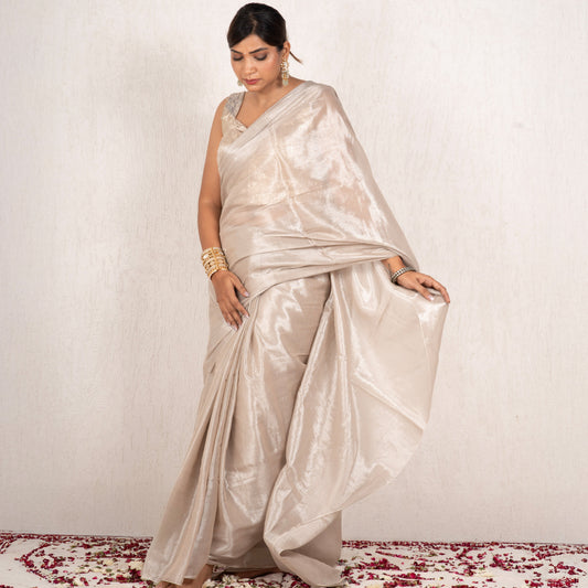 Woman wearing a beige saree with a white background