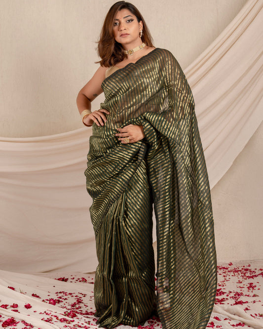Woman in a green saree standing on a white fabric background with red flower petals.
