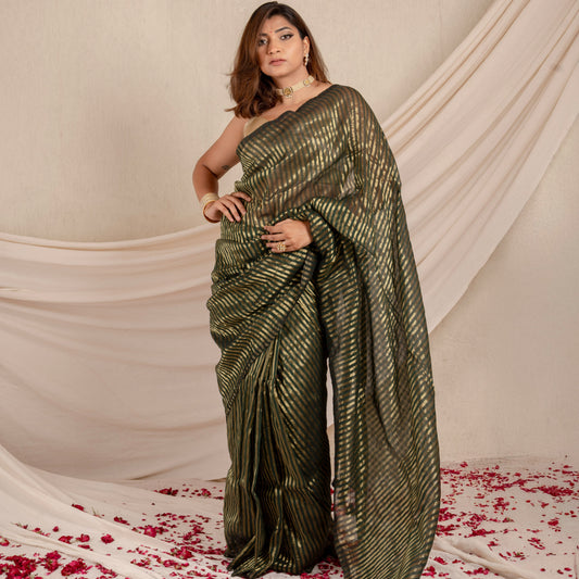 Woman in a green saree standing on a white fabric background with red flower petals.